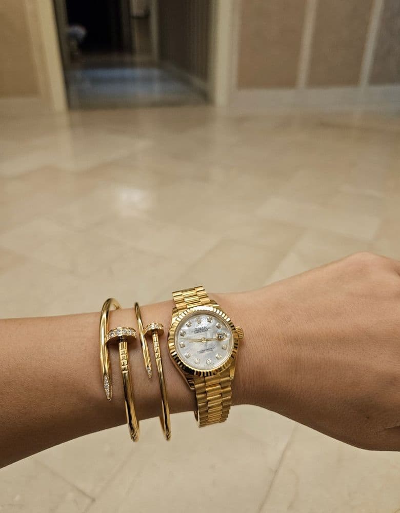 Layering jewelry with a Rolex gold Datejust with ten diamond markers.