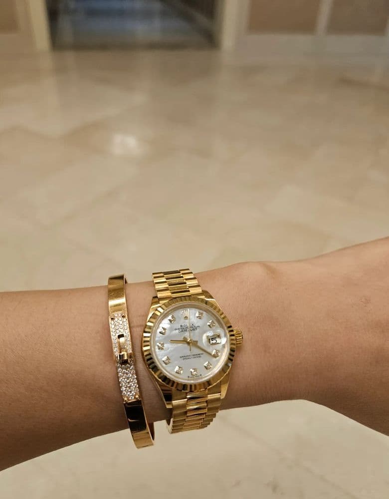 Layering jewelry with a Rolex gold Datejust with ten diamond markers.