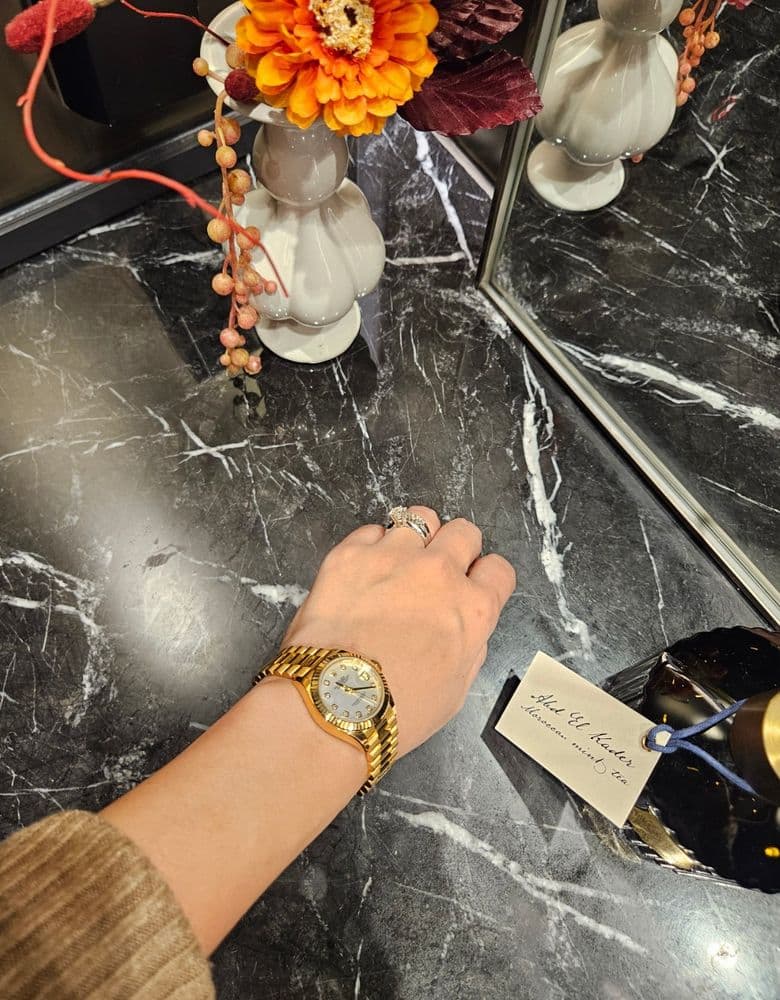 Layering jewelry with a Rolex gold Datejust with ten diamond markers.