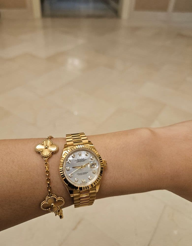 Layering jewelry with a Rolex gold Datejust with ten diamond markers.