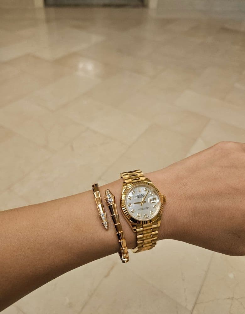 Layering jewelry with a Rolex gold Datejust with ten diamond markers.