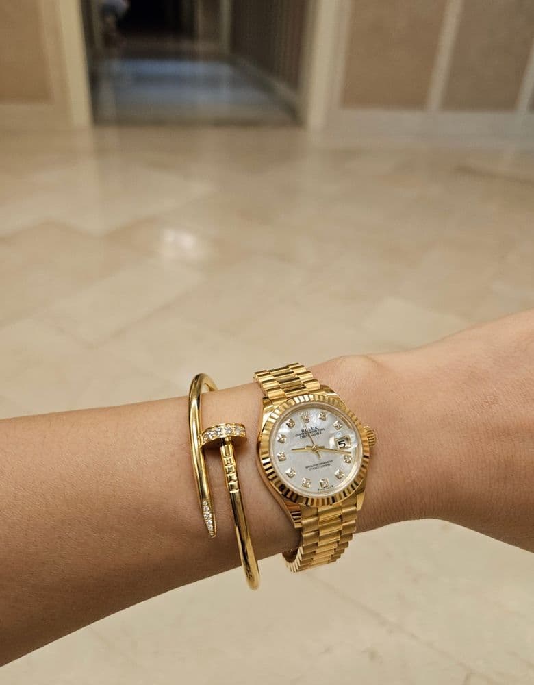 Layering jewelry with a Rolex gold Datejust with ten diamond markers.